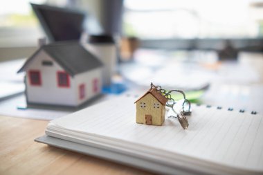 Real estate sales documents and model homes are placed on tables inside real estate sales offices to prepare prospective buyers to sign real estate sales contracts with dealers.