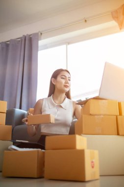 İnternet üzerinden müşteri siparişi paketini kontrol eden kadın, KOBİ 'li bir girişimci olduğu ve internet üzerinden pazarlamak için telefon ve tabletini kullandığı için ev ofisinde yalnızdır. konsept çevrimiçi satış işi