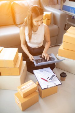 İnternet üzerinden müşteri siparişi paketini kontrol eden kadın, KOBİ 'li bir girişimci olduğu ve internet üzerinden pazarlamak için telefon ve tabletini kullandığı için ev ofisinde yalnızdır. konsept çevrimiçi satış işi