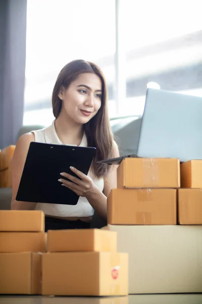 woman checking package of goods from customer online order is alone in her home office as she is an SME entrepreneur and uses her phone and tablet to market online. concept online sales business