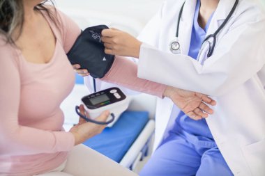 Doktor yaşlı bir hastaya kan basıncının anormal yüksek olup olmadığını anlamak için tansiyon monitörü kullanıyor. Çünkü hipertansiyon genelde yaşlılara olur ve tehlikelidir..