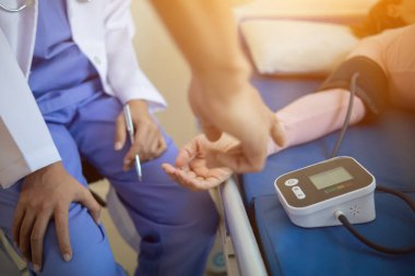 Doktor yaşlı bir hastaya kan basıncının anormal yüksek olup olmadığını anlamak için tansiyon monitörü kullanıyor. Çünkü hipertansiyon genelde yaşlılara olur ve tehlikelidir..