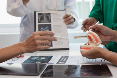 Diş hekimlerinden oluşan bir ekip konferans odasında hasta diş ağrısını tedavi ediyor. Doktorlar ve dişçiler, iltihaplanma nedeniyle ağrıya yol açan kanal tedavisi için bir araya geliyorlar..