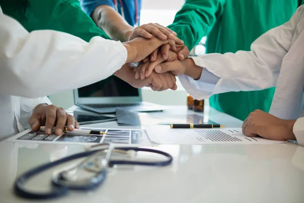 The medical team joins hands after the meeting and discusses the treatment of severely ill patients and can come to a conclusion on the surgical treatment of the patient. Medical team meeting concept