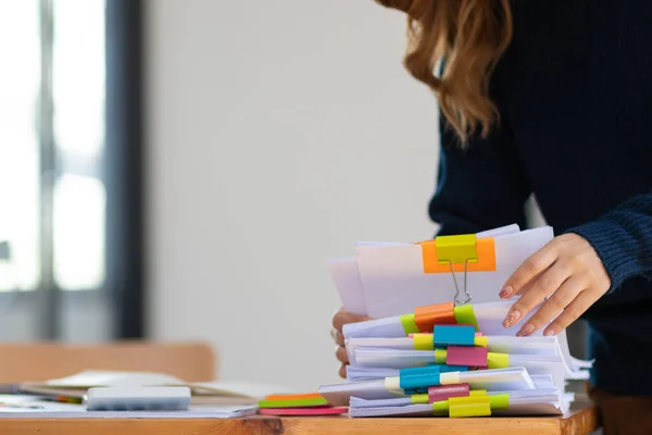 stock image secretary searches through stacked documents on desk in office to find lease within stacked documents just before meeting. concept difficulty in finding hire purchase contract from stacked documents