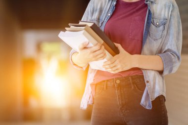 Avukat olmak için sınava girmeden önce hukuku incelemek ve anlamak için elinde kitap tutan genç bir kadın. Avukat olmak için sınava girmeden önce hukuku anlamak ve öğrenmek için kitap okuma kavramı.