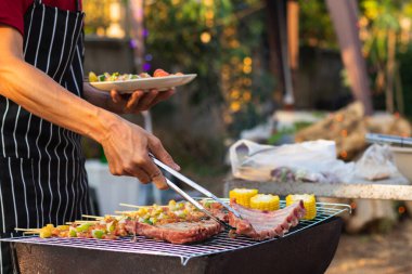 Barbekü partisi için et ve şiş malzemeleri barbekü yapmak ve ailenin barbekü partisine katılması için ızgaraya konur. parti arkaplan resmi metin için kopyalama alanına sahip.