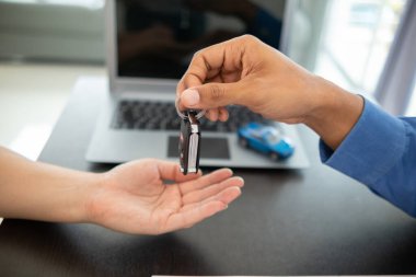 Araba galerisi satıcısı satış sözleşmesi tamamlandıktan sonra anahtarları müşteriye teslim etti. Huzur için güvenilir bir satıcıyla araba alıp satma kavramı..