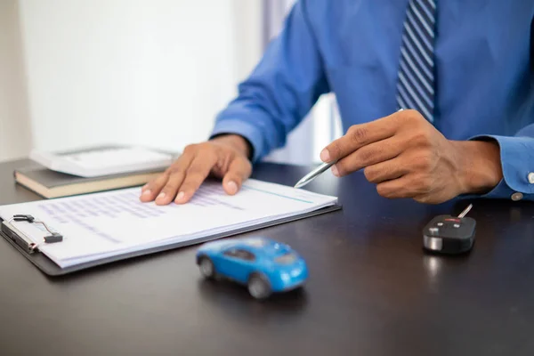 The car dealers of the car showrooms bring the car sales contract documents to the customers and explain the loan and interest rates to the customers before signing the sales contract for accuracy.