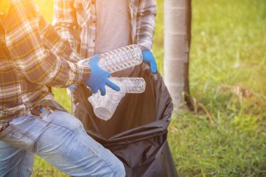 İki çalışan, geri dönüşüm için plastik şişe ve geri dönüşümlü atık toplamak için siyah çöp torbaları kullanıyor. Plastik atıkları geri dönüşüm için sıralama kavramı
