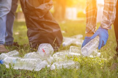 İki çalışan, geri dönüşüm için plastik şişe ve geri dönüşümlü atık toplamak için siyah çöp torbaları kullanıyor. Plastik atıkları geri dönüşüm için sıralama kavramı