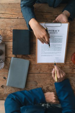 Satış sözleşmesi avukatlık bürosundaki masaya kondu çünkü şirket avukat ofisini yasal danışman olarak tuttu ve sözleşmeyi hazırladı böylece müvekkil doğru sözleşmeyi imzalayabilecekti..