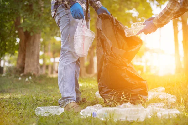 men collect plastic bottles on lawns and walkways in park and put them in bags to help keep them clean They can also collect plastic bottles for recycling. reducing environmental problems by recycling