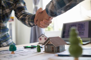 Mimarlar ve mühendisler, inşaat projesinin planlanmasında işbirliği ve başarıyı tartışmak için el ele tutuşuyorlar. Mühendisler ve mimarlar başarılı olduktan sonra el ele tutuşur.