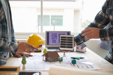 Yenilenebilir enerji mühendislerinden oluşan bir ekip, güneş panellerinin ev desteklerinin yapısını oluşturmak için mimarlarla konuşuyor. Yenilenebilir enerji olarak kullanılacak güneş pilleri kurulumu kavramı