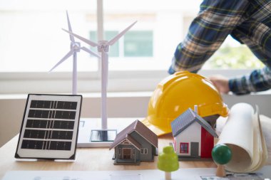 Yenilenebilir enerji mühendislerinden oluşan bir ekip, güneş panellerinin ev desteklerinin yapısını oluşturmak için mimarlarla konuşuyor. Yenilenebilir enerji olarak kullanılacak güneş pilleri kurulumu kavramı