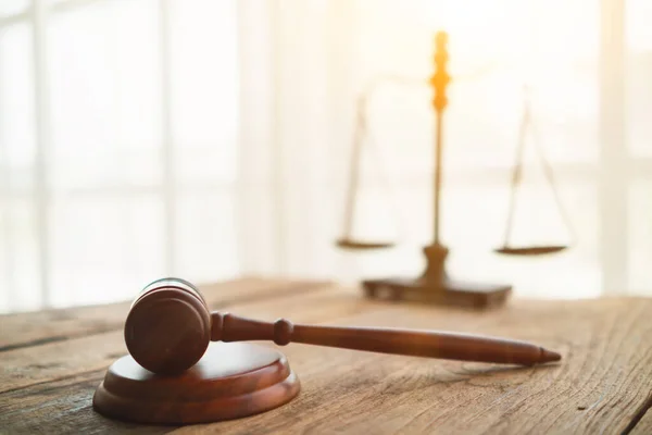 Tahta sehpa üzerindeki tokmak hukuk müşavirliği bünyesinde adaleti temsil eden terazinin bulanık arkaplanı, iyi görünümlü hukuk müşavirliği, yasal tavsiye isteyenleri daha güvenilir kılacaktır..