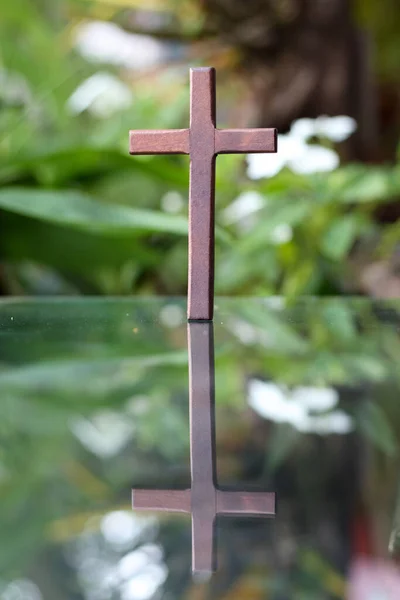 基督教中代表上帝的十字架被放在镜子上 其反光可以在模糊的自然背景下看到 交叉的背景是模糊的 并有复制空间在旁边为文本 — 图库照片
