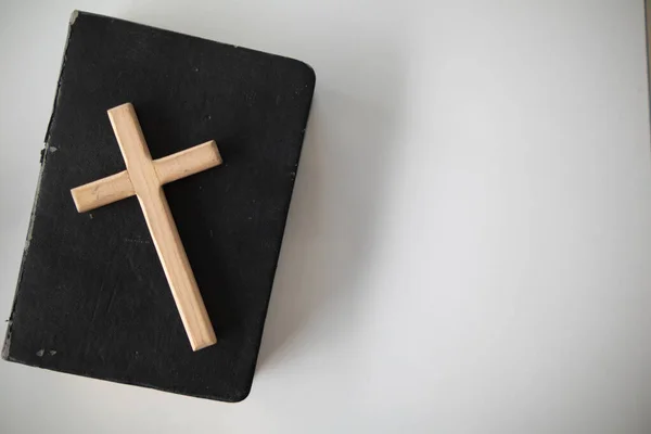 十字架代表放在圣经上的上帝 圣经是根据基督教信仰教导上帝的 十字架和圣经被放在桌子上的房间里 他们正准备为上帝祈祷 — 图库照片
