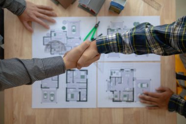 İnşaat mühendisi, mimarlık ekibinin tasarladığı ve mühendislik ekibinin kabul ettiği konut projesini kutlamak için mimarla el ele veriyor. Tebrikler için tokalaşma konsepti