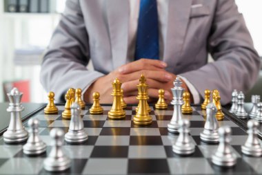 Genç işadamı satranç oyununda satranç hamlesini kazanmayı planlıyor. Başarılı ve muzaffer iş yolunu temsil ediyor. Zafere ulaşmak için stratejik iş stratejisini temsil eden satranç kavramı.