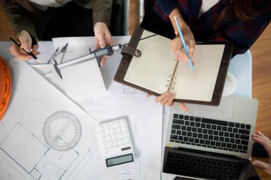Mimarlar ve mühendisler, inşaatın standartlara uygun ve zamanında tamamlandığından emin olmak için konut inşaatının nasıl tasarlanacağını tartışıyor. Mühendisler ve mimarlardan oluşan bir ekip bina tasarımı ve yapısını tartıştı.