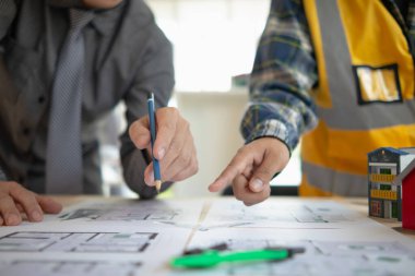 Construction engineers discuss and exchange ideas with architects to improve house plans to meet customer needs. A concept for exchange of design ideas between construction engineers and architects. clipart