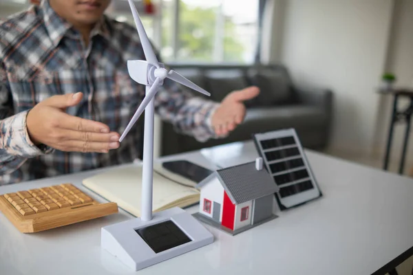 On desk of engineers lay model of house And solar panels to use in planning installation of solar panels to  house in order to get most cost effective energy from installing solar panels.