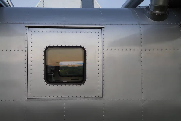 metal wall in background is wall of an airplane fuselage that has been repurposed as residential vehicle. metal wall with metal rivets hold joints together is metal wall of an airplane and copy space