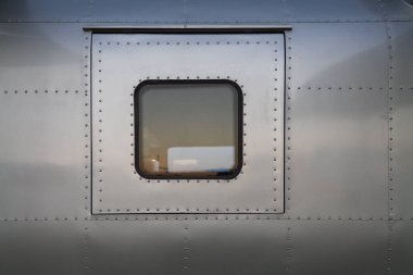 Arka plandaki metal duvar, yerleşim aracı olarak yeniden tasarlanmış bir uçak gövdesinin duvarı. Metal perçinli metal duvar, eklemleri bir uçağın metal duvarı ve kopyalanmış uzayı bir arada tutar.