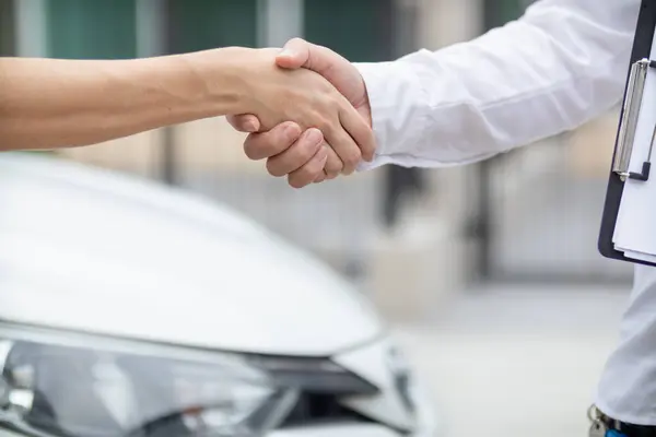 Car dealers shake hands with customers to congratulate them when car loan and sales contract are approved before dealer hands car key to customer. entering into sales contract with trusted distributor