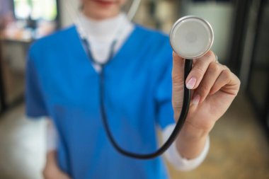 Steteskop tutan üniformalı kadın doktor bir hastayı muayene etmek için bekliyor. Kadın bir doktor hastaları tedavi etmek için steteskop tutuyor. Tıbbi metin eklemek için Boşluğu Kopyala