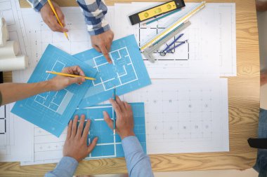 Mimarlar ve inşaat mühendisleri inşaat projesinin tamamlanmasını hesaplamak için yapı planlarını tartışmak üzere bir araya geliyorlar. Emlak inşaat işi konsepti.