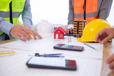 Mimarlar ve inşaat mühendisleri inşaat projesinin tamamlanmasını hesaplamak için yapı planlarını tartışmak üzere bir araya geliyorlar. Emlak inşaat işi konsepti.