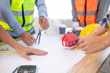 Mimarlar ve inşaat mühendisleri inşaat projesinin tamamlanmasını hesaplamak için yapı planlarını tartışmak üzere bir araya geliyorlar. Emlak inşaat işi konsepti.