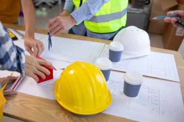 Mimarlar ve inşaat mühendisleri inşaat projesinin tamamlanmasını hesaplamak için yapı planlarını tartışmak üzere bir araya geliyorlar. Emlak inşaat işi konsepti.