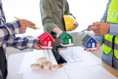 Mimarlar ve inşaat mühendisleri inşaat projesinin tamamlanmasını hesaplamak için yapı planlarını tartışmak üzere bir araya geliyorlar. Emlak inşaat işi konsepti.