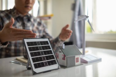 Mühendisler masasında, güneş panellerinin kurulumunu planlamak için güneş panelleri ve ev için kullanılacak ev modelleri ve güneş panelleri vardı..