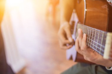 Genç bir adam sahneye çıkmadan önce sahnede gitar çalma hatasını azaltmak için bir müzik çalışma odasında gitar çalma pratiği yapıyor. Yakından Genç Adam pratik için gitar akorları tutuyor..