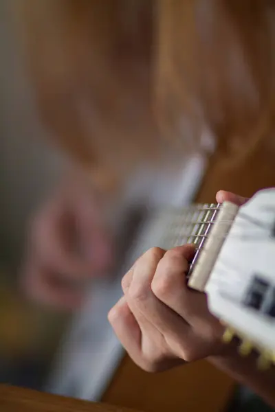 A young woman is practicing acoustic guitar to perform on stage in a music practice room before performing in order to reduce mistakes. Close Up, a woman\'s hand holding guitar chords for practice.