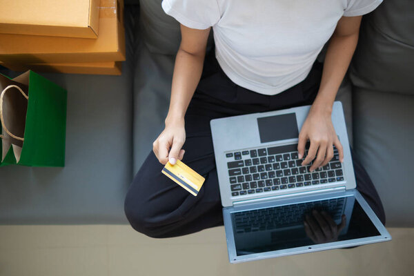 woman sitting in her room is happily shopping for gifts online with her credit card as she prepares for Christmas. woman uses laptop to access an online shopping website and pay with her credit card.