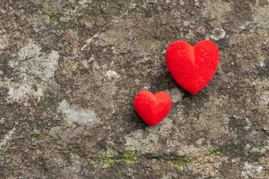 Two red hearts placed on a concrete background to show the love, kindness, and friendship that is between the friend and lover on Valentine's Day. The concept of friendship, love and compassion clipart