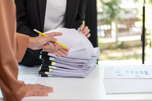 A young secretary receives a pile of documents to find important information for the company manager to use in a meeting. The concept of finding important documents from piles of overlapping documents