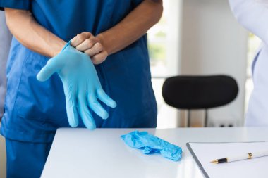 Doktor mavi lastik eldiven takıyor. Hastayla doğrudan teması engelliyor. Çünkü virüsün hasta vücuduna kadar izi sürülebilir ve tıbbi lastik eldivenler de hastaya bulaşmasını engelliyor.