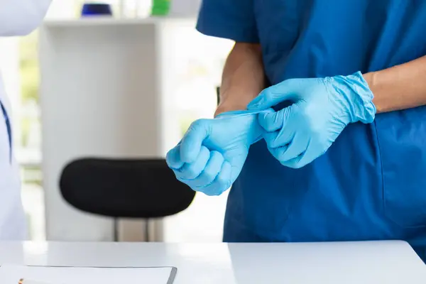 doctor is wearing blue rubber gloves prevent direct contact with patient because virus may be traced to patient body and medical rubber gloves also help prevent virus from being transmitted to patient