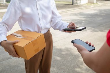 KOBİ işletme operatörü, uygulama çevrimiçi alışverişi ile çevrimiçi pazarlamaya katıldıktan sonra ürünleri almaya gelecek olan teslimat şirketi için ürünleri paket kutusuna koyup teftiş ediyor.