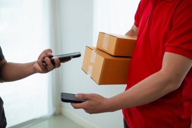 KOBİ işletme operatörü, uygulama çevrimiçi alışverişi ile çevrimiçi pazarlamaya katıldıktan sonra ürünleri almaya gelecek olan teslimat şirketi için ürünleri paket kutusuna koyup teftiş ediyor.