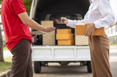 KOBİ işletme operatörü, uygulama çevrimiçi alışverişi ile çevrimiçi pazarlamaya katıldıktan sonra ürünleri almaya gelecek olan teslimat şirketi için ürünleri paket kutusuna koyup teftiş ediyor.