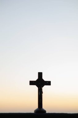 The silhouette of a cross on the background of a twilight sunset is a symbol of God and the cross is also believed to be of His divinity. The cross is a symbol of God loving kindness for all people. clipart