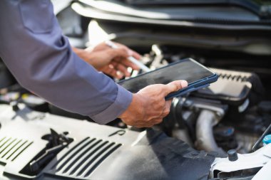Araç hizmet merkezi tamircileri araba ve motoru kontrol ediyor. Kullanıma hazır ve merkezin garantisine göre mükemmel durumda olduklarından emin olun. Güvenli sürüş için periyodik araç denetimleri.